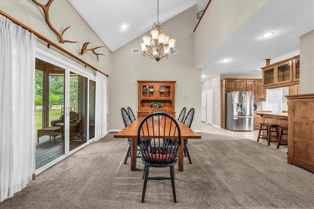 613 Bone Road, Valley Mills, TX 76689 Vaulted ceiling dining area featuring a chandelier, sliding glass doors, and a neutral wall palette
