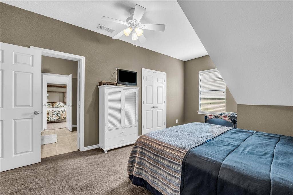 613 Bone Road, Valley Mills, TX 76689 Carpeted room featuring a ceiling fan with light fixture, a window with horizontal blinds, and a sloped ceiling detail