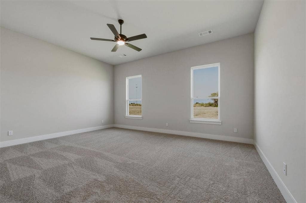 2305 Quartz Street, Krum, TX 76249 Spacious room featuring neutral carpeting, a ceiling fan with integrated lighting, two windows, and a vaulted ceiling