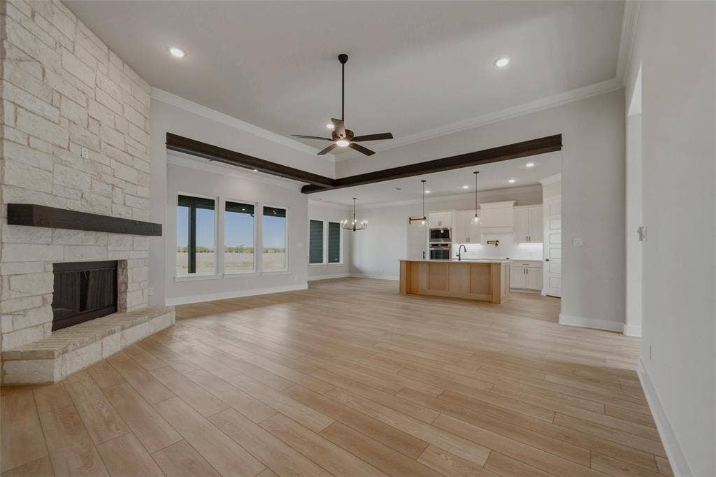 2305 Quartz Street, Krum, TX 76249 Spacious living area featuring light wood-finish flooring and a stone-clad fireplace