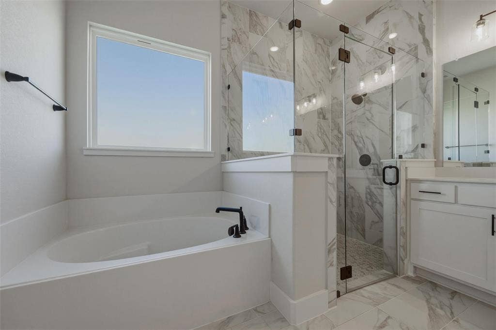 2305 Quartz Street, Krum, TX 76249 Soaking tub with black fixtures, walk-in shower with clear glass enclosure, white marble-look wall tile, dual vanity with white cabinetry, and large format floor tile