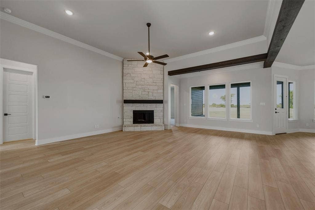 2305 Quartz Street, Krum, TX 76249 Expansive room featuring wood-finish flooring, a stone-clad fireplace with a dark wood mantle, and exposed dark wood ceiling beams
