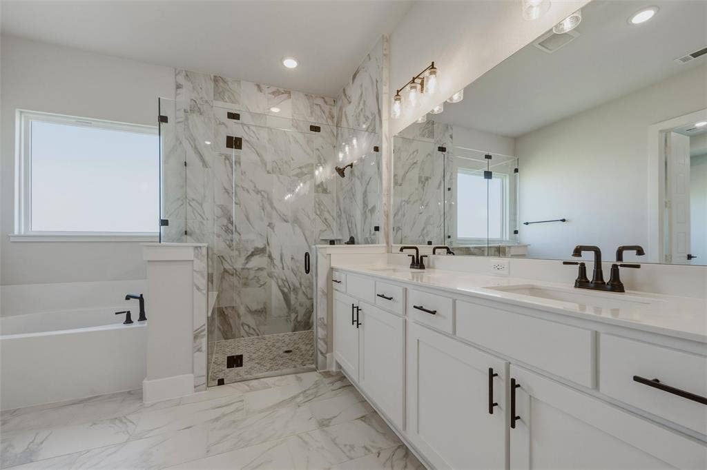 2305 Quartz Street, Krum, TX 76249 Dual vanity with white cabinetry and dark bronze hardware, walk-in shower with glass enclosure, separate soaking tub with dark bronze fixtures, marble-look tile flooring, and integrated lighting