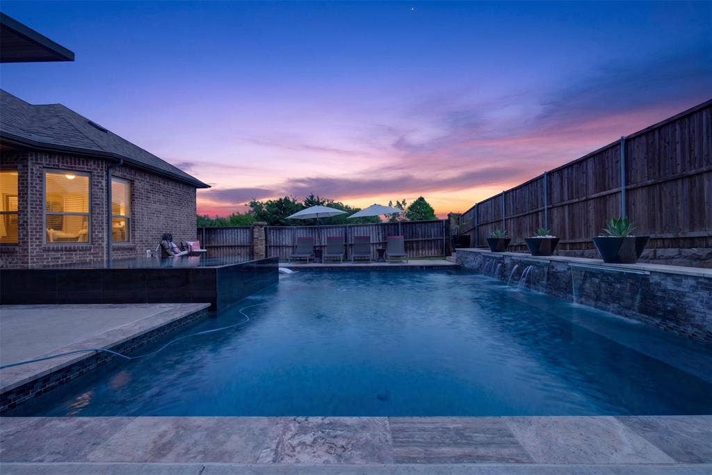 Pool and spa are framed by the covered patio and beautifully lit outdoor living space.