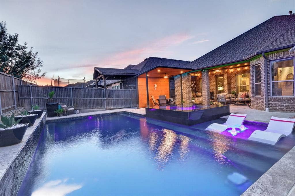 Twilight view captures the pool, spa and warm glow of the covered outdoor living area.