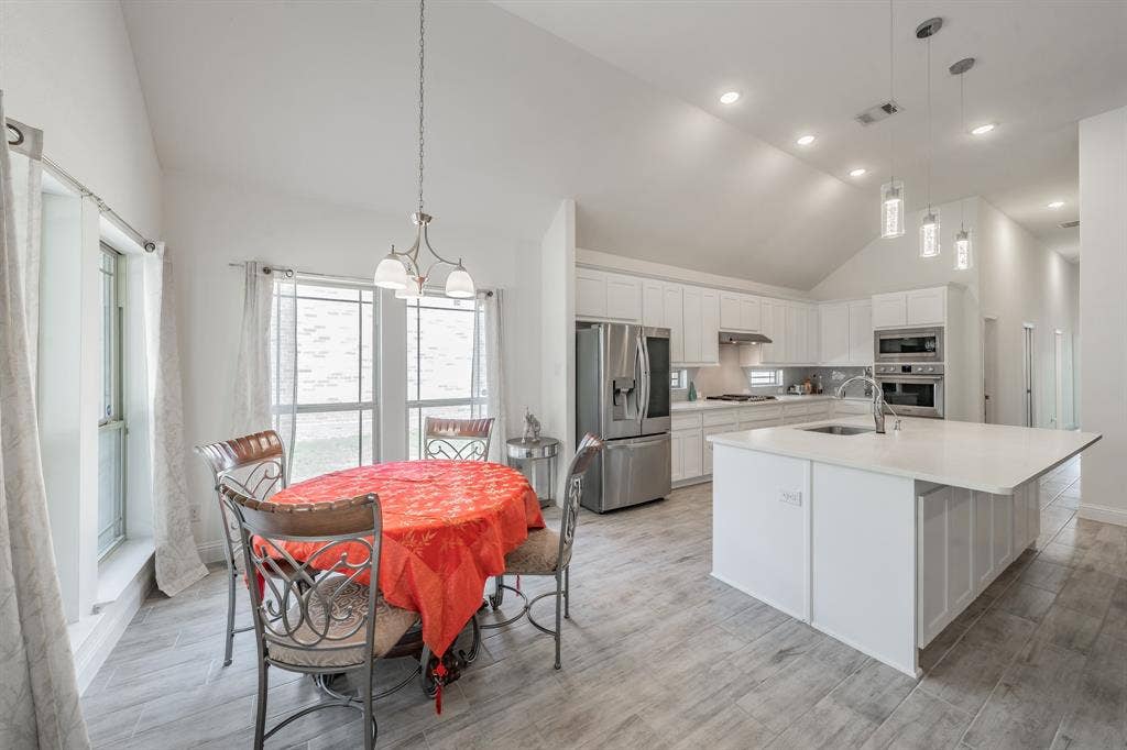 Kitchen featuring stainless steel appliances, an island with sink, and breakfast nook