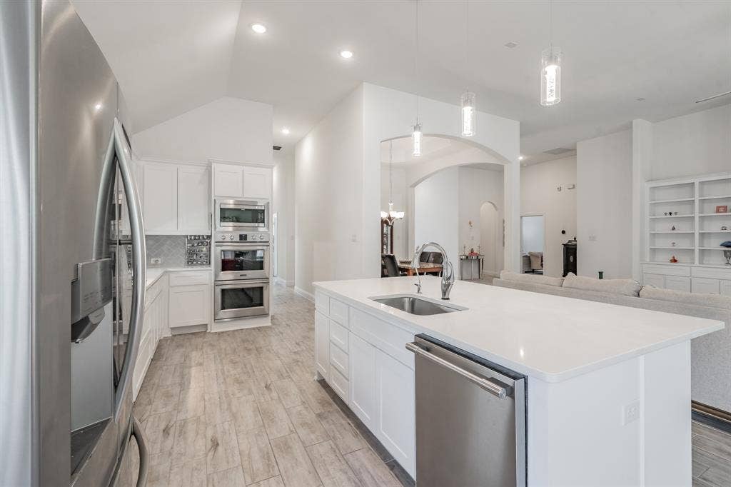 Kitchen with appliances with stainless steel finishes, an island with sink, white cabinetry, and sink