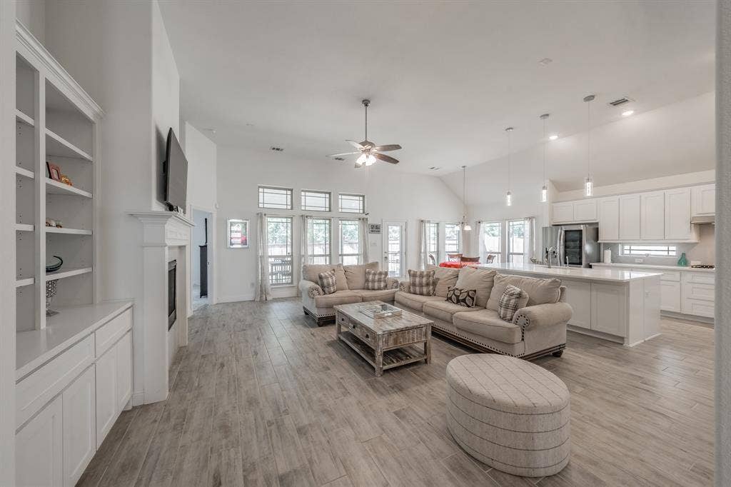 Open concept featuring light wood-type tile flooring, high vaulted ceiling, and ceiling fan
