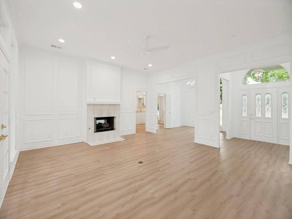 4312 Avonshire Lane, Plano, TX 75093 Expansive interior space featuring light wood-finish flooring, a tile-surround fireplace with hearth, recessed lighting, and decorative wall molding