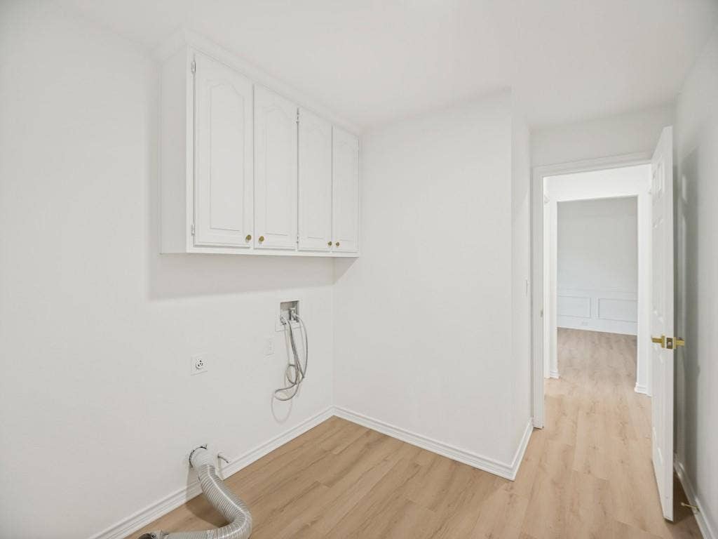 4312 Avonshire Lane, Plano, TX 75093 Laundry area featuring light wood-finish flooring, white cabinetry with brass-finish hardware, and crisp white walls