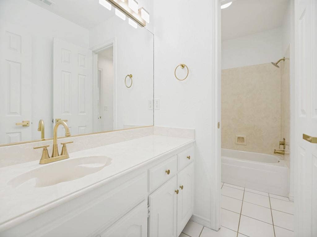 4312 Avonshire Lane, Plano, TX 75093 Bathroom featuring a white vanity with gold-finish hardware, integrated sink, and full-width mirror