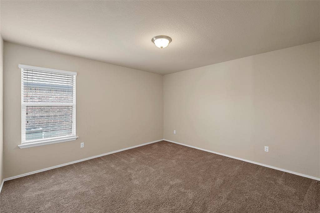 Room featuring neutral wall paint, brown carpet, a single window with white blinds, and a flush-mount ceiling light fixture