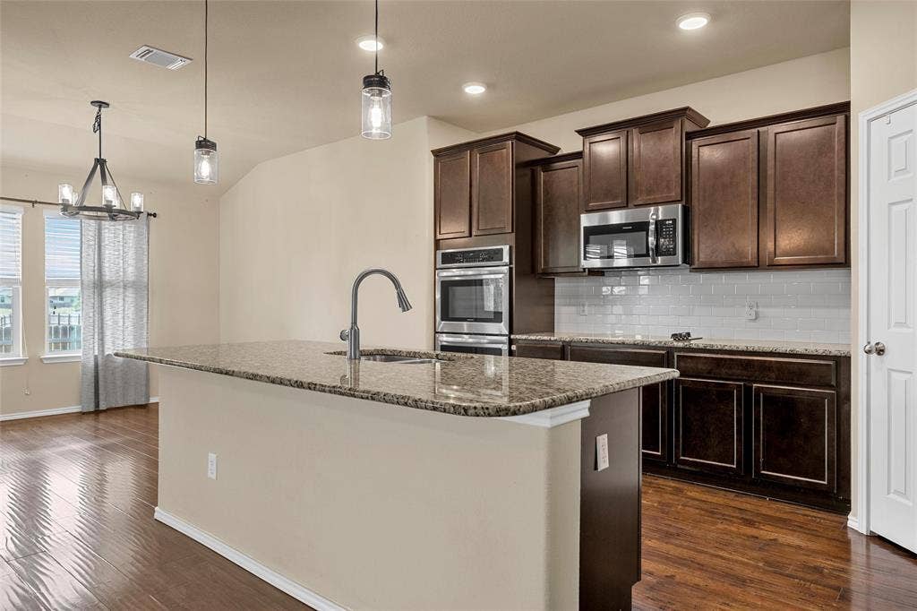Kitchen island featuring a single-basin sink, gooseneck faucet, and granite countertop