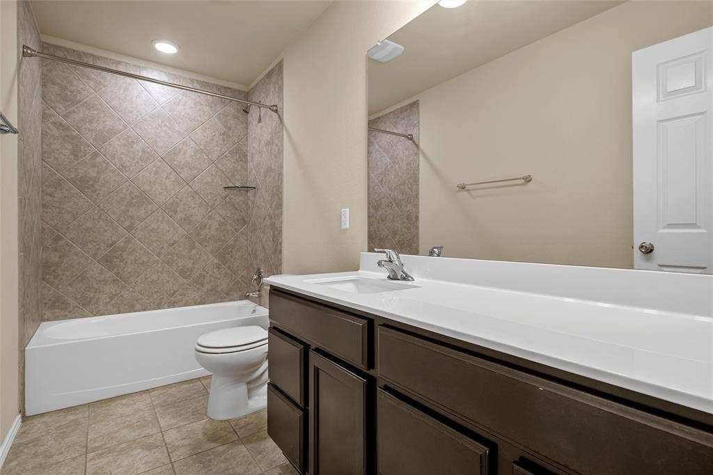 Bathroom featuring a white vanity with a white countertop, dark wood-finish cabinetry, a large wall-mounted mirror, and a shower-tub combination with diagonal tile surround