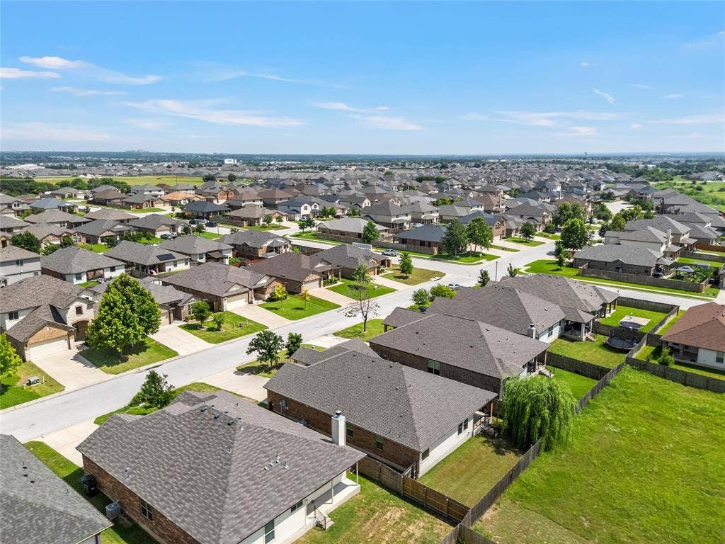 Aerial perspective of a residential neighborhood with uniformly designed homes featuring shingle roofs, paved streets, and green lawns