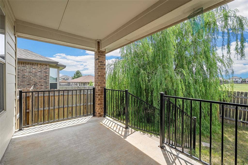 Covered patio featuring a concrete surface, black metal railings, and a brick support column
