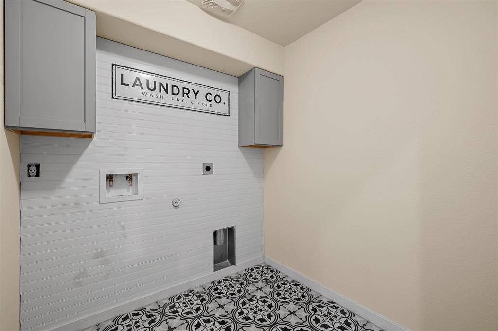 Dedicated laundry area featuring patterned tile flooring and white shiplap-style wall paneling
