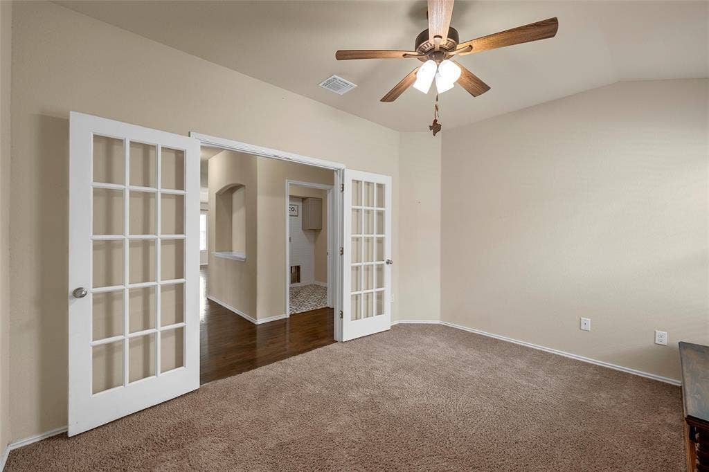Room featuring twin French doors, vaulted ceiling, and a ceiling fan with light fixture