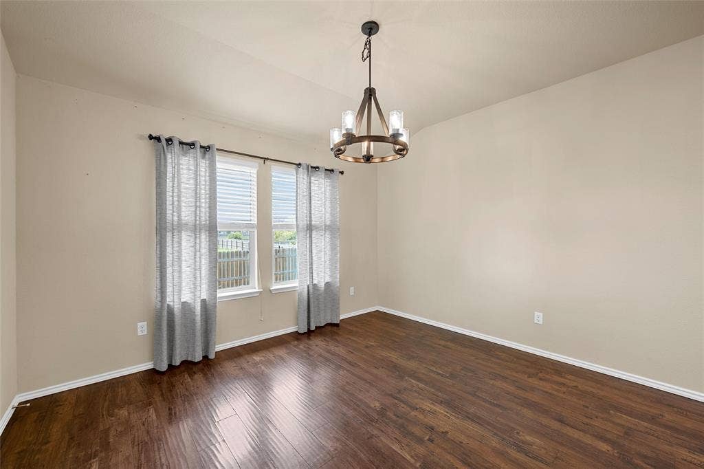 Open-concept room featuring wood-finish flooring, neutral wall tones, and a contemporary chandelier