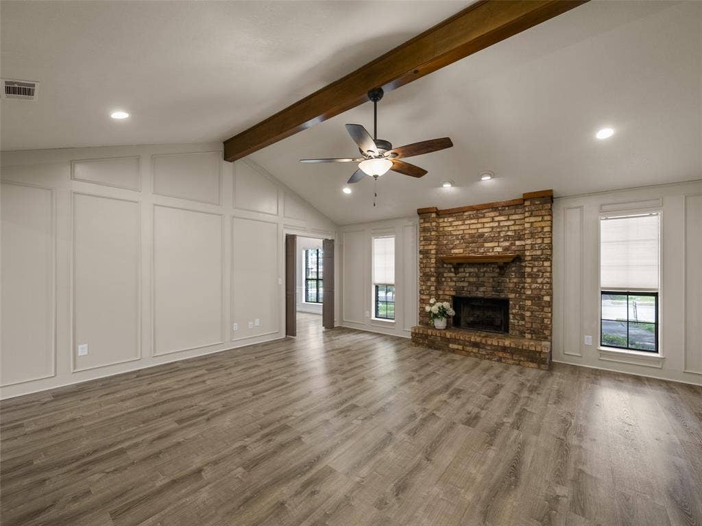 4100 Emerson Drive, Plano, TX 75093 The masonry fireplace with gas starter is flanked by two windows and the room is accentuated with a wood-beamed cathedral ceiling. Picture frame paneling surrounds the walls.