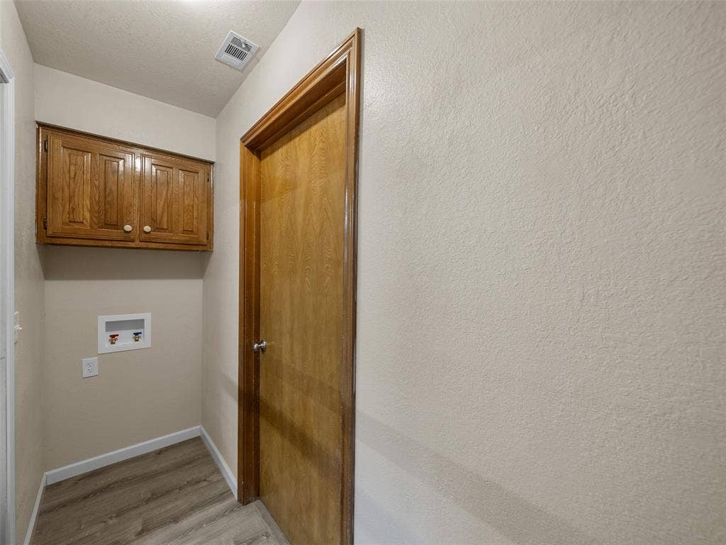 4100 Emerson Drive, Plano, TX 75093 The full-size laundry area has built-in cabinetry and the washer is on one side and the dry is one the opposite side. The entry to the garage is in the middle.