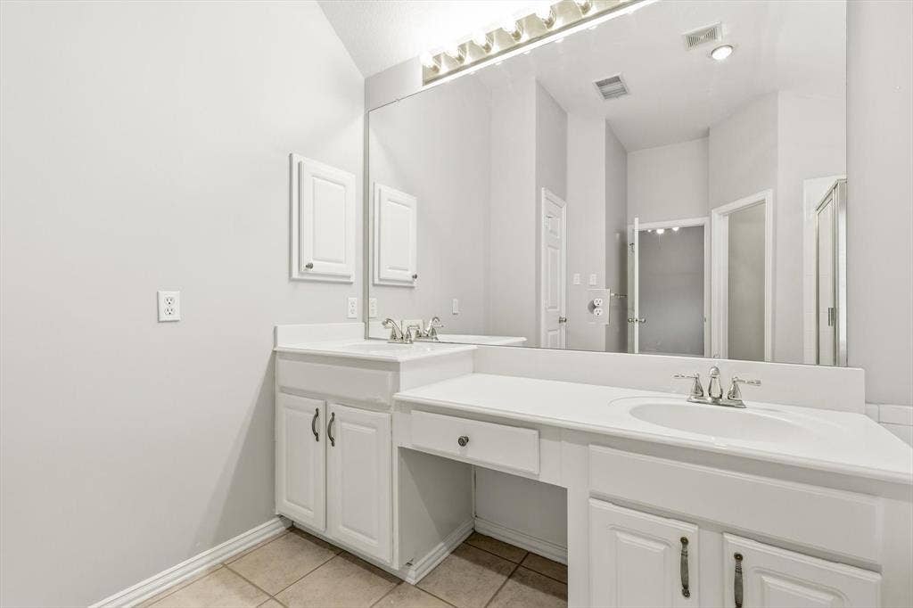 Double vanity with integrated sinks, white cabinetry, and a dedicated vanity area