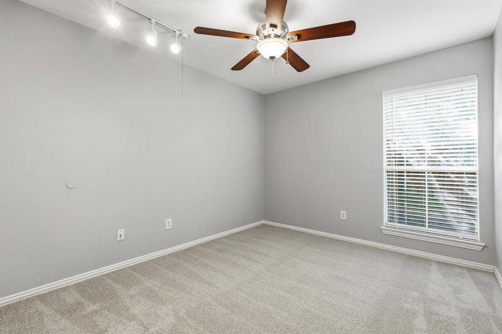 Bedroom featuring neutral gray walls, light-toned carpet, white trim, a ceiling fan with light fixture, and a window with blinds