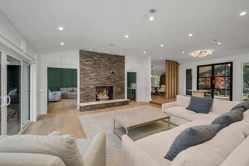 6275 Preston Creek Drive, Dallas, TX 75240 Living area with light wood-type flooring, a stone fireplace, recessed lighting, vaulted ceiling, and a decorative wall