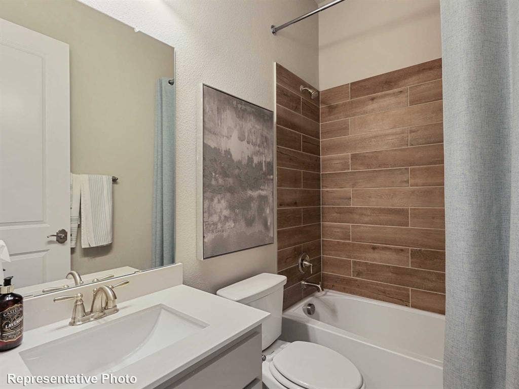 Bathroom featuring a single vanity with an integrated sink, brushed nickel faucet, and a shower-tub combination