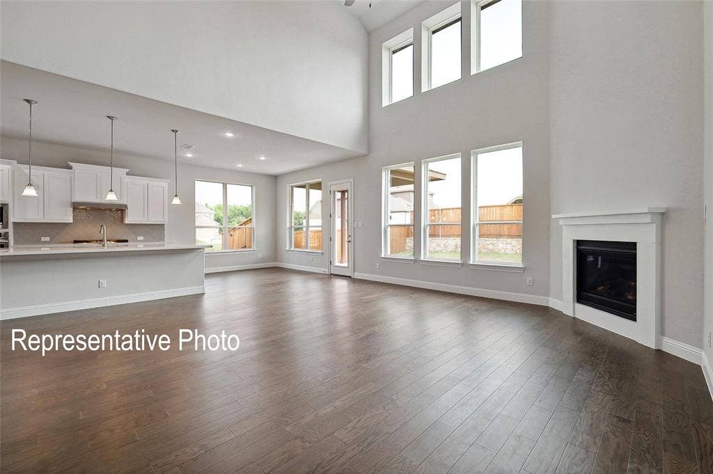 2297 Slate Drive, Waxahachie, TX 75167 Spacious living area featuring wood-finish flooring, a fireplace with a white mantel, and high ceilings