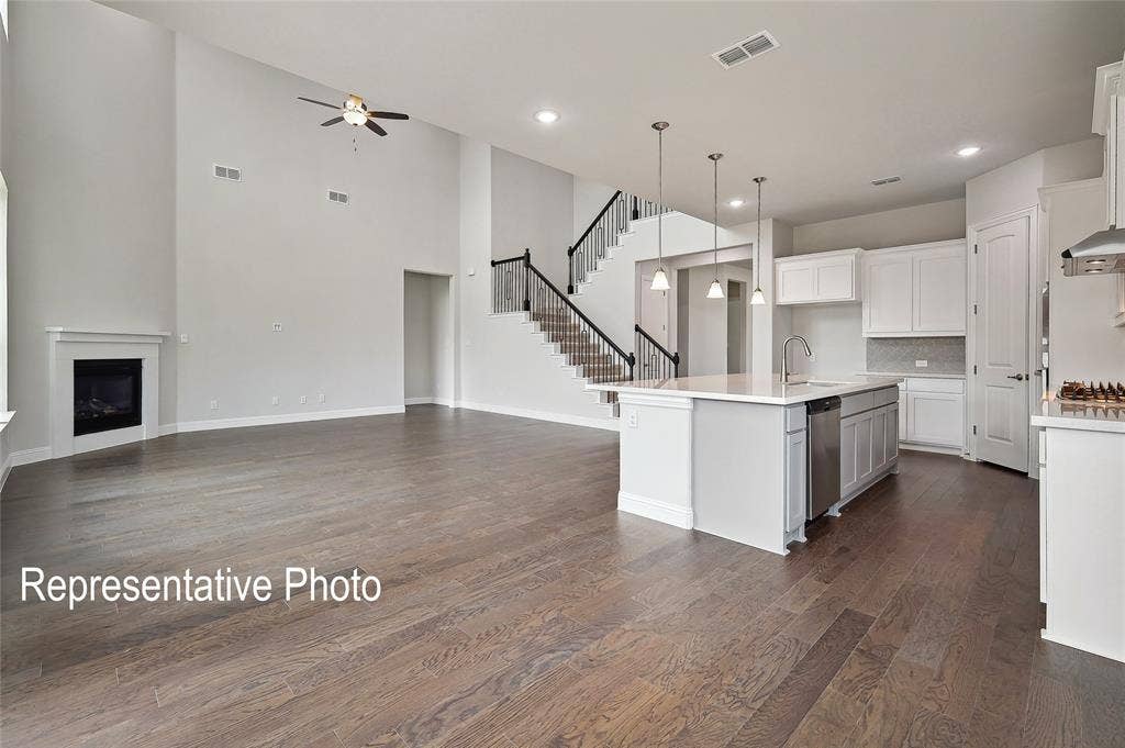 2297 Slate Drive, Waxahachie, TX 75167 Spacious living area featuring high vaulted ceilings, a built-in fireplace with a white mantel, and wood-finish flooring