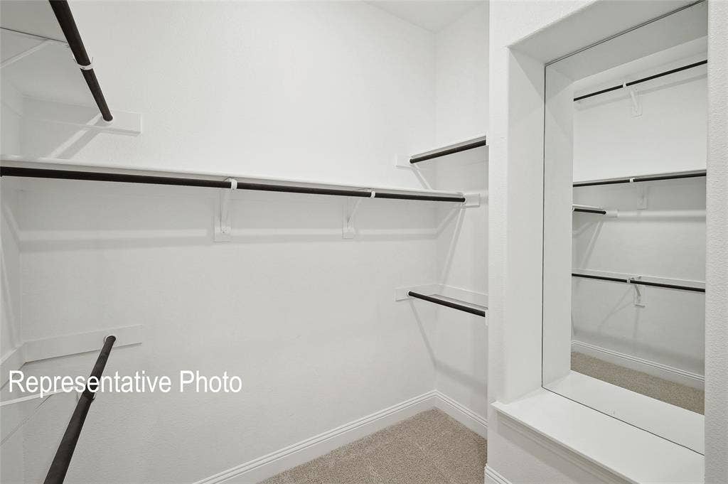 2297 Slate Drive, Waxahachie, TX 75167 Spacious walk-in closet featuring multiple shelving units, built-in hanging rods, and neutral-toned carpeting