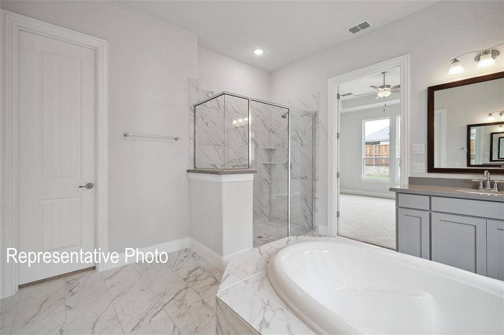 2297 Slate Drive, Waxahachie, TX 75167 Soaking tub with surrounding tile, walk-in shower with glass enclosure and marble-finish tile, dual vanity with undermount sinks, wood-frame mirror, and recessed lighting