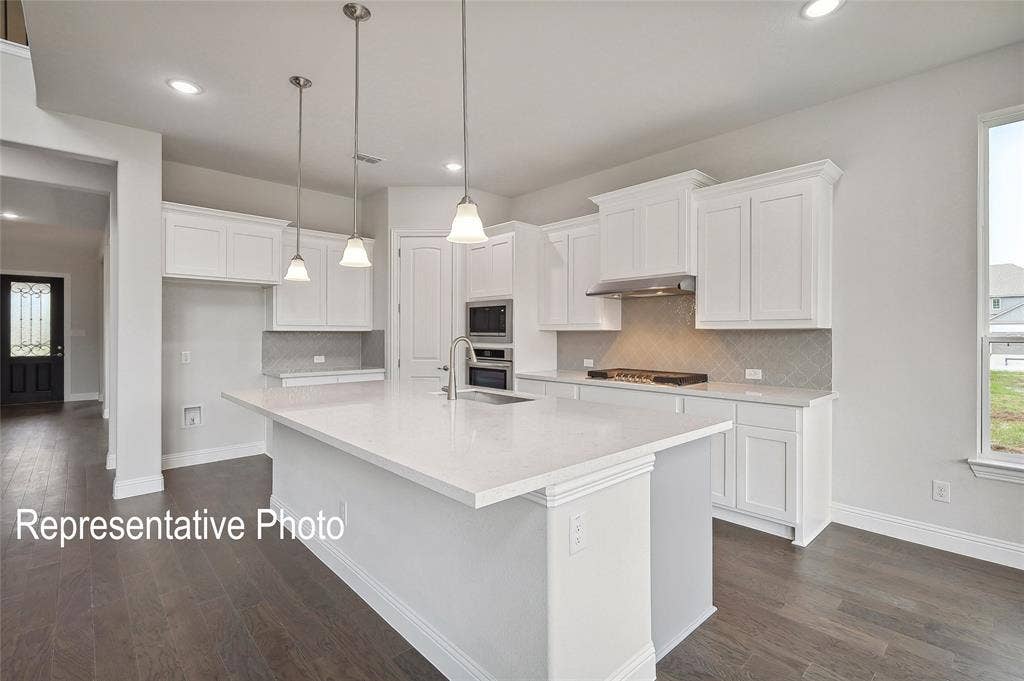 2297 Slate Drive, Waxahachie, TX 75167 Kitchen featuring a large central island with pendant lighting, white cabinetry, integrated appliances, a tiled backsplash, and wood-finish flooring