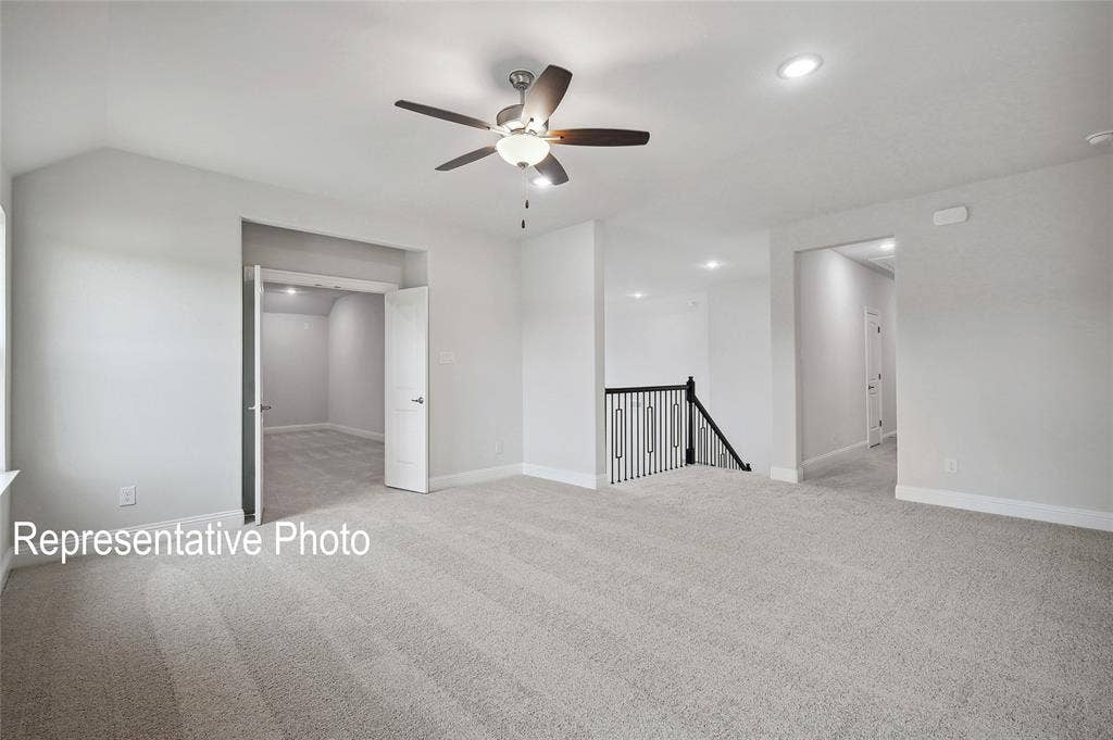 2297 Slate Drive, Waxahachie, TX 75167 Expansive carpeted room featuring a ceiling fan with integrated lighting, recessed lighting, and a black wrought iron staircase railing