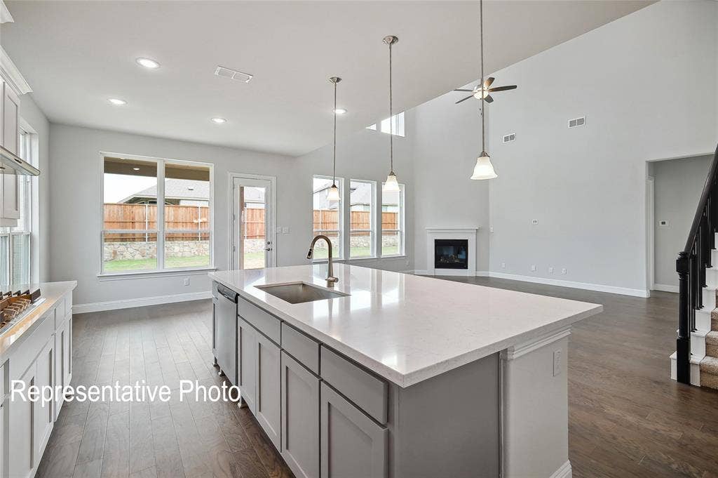 2297 Slate Drive, Waxahachie, TX 75167 Open-concept living space featuring a central kitchen island with a built-in sink and pendant lighting