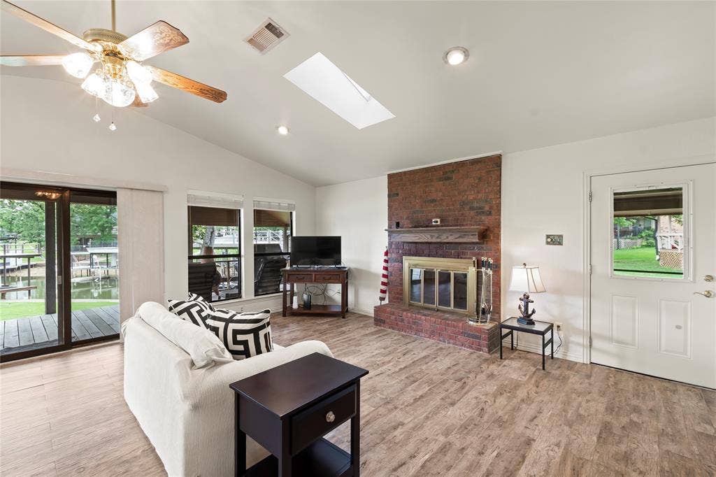 1524 Villa Cove Drive, Tool, TX 75143 Bright and airy living room with open floor plan, wood-grain porcelain tile, and large windows bringing in natural light and lake views.