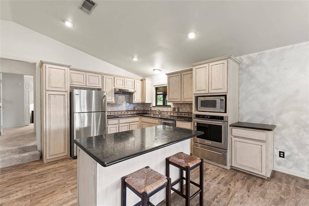 1524 Villa Cove Drive, Tool, TX 75143 Traditional kitchen featuring stainless steel appliances, built-in oven with warming drawer, electric cooktop, high-end granite countertops, and plenty of storage.