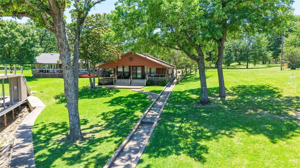 1524 Villa Cove Drive, Tool, TX 75143 Charming single-story lake home with wraparound covered porch and beautifully landscaped lots, perfectly situated on 120 feet of waterfront.