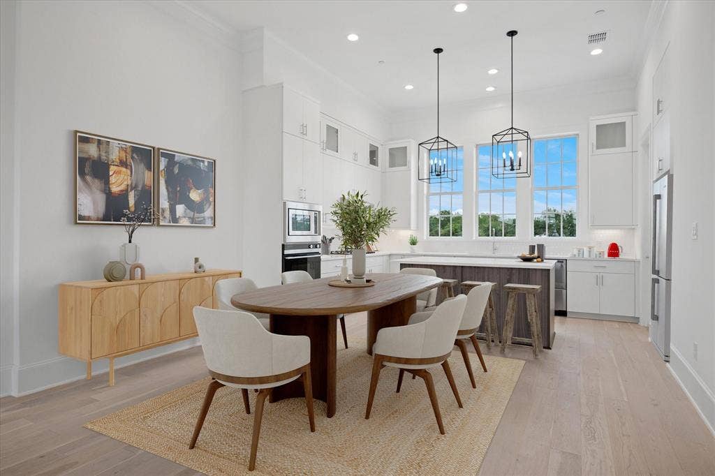 Open-concept kitchen and dining area featuring light wood-finish flooring, white cabinetry, and a large center island with seating