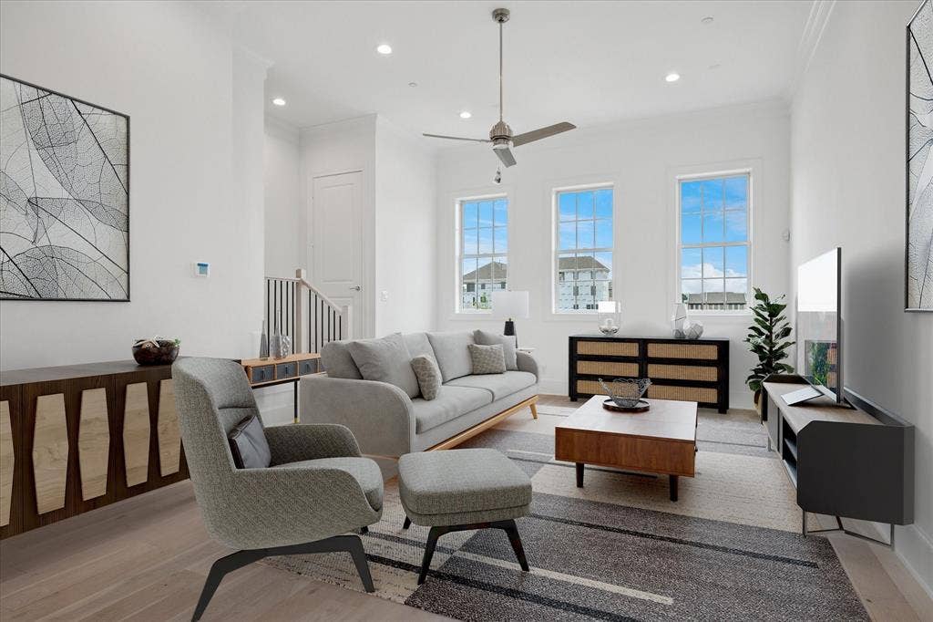 Bright living area featuring high ceilings, recessed lighting, wood-finish flooring, and multiple large windows