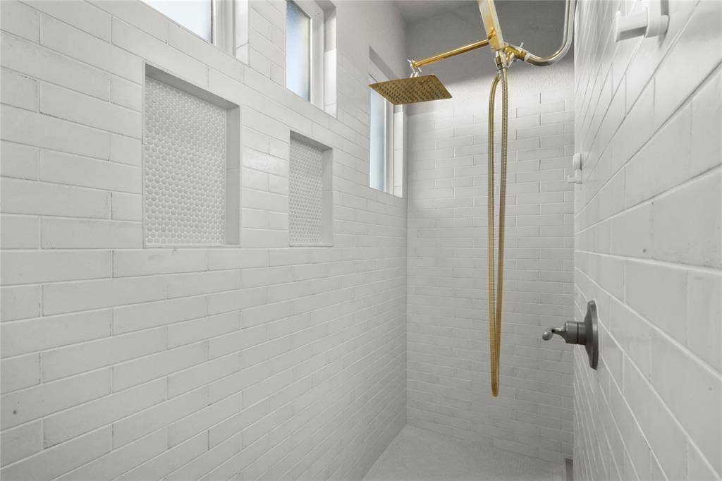 Shower with full-height white subway tile, rain shower head, hand-held shower, recessed shelving with penny tile accents, and transom windows
