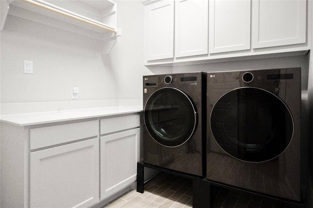 Dedicated laundry space featuring white shaker-style cabinetry, a light-toned countertop, and light-toned floor tile