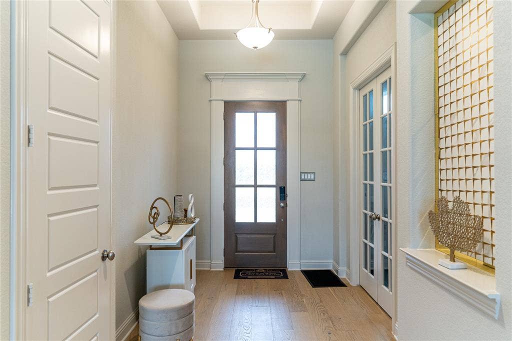 Inviting entryway featuring wood-finish flooring, a tray ceiling with a semi-flush mount light fixture, and a paneled front door with clear glass inserts