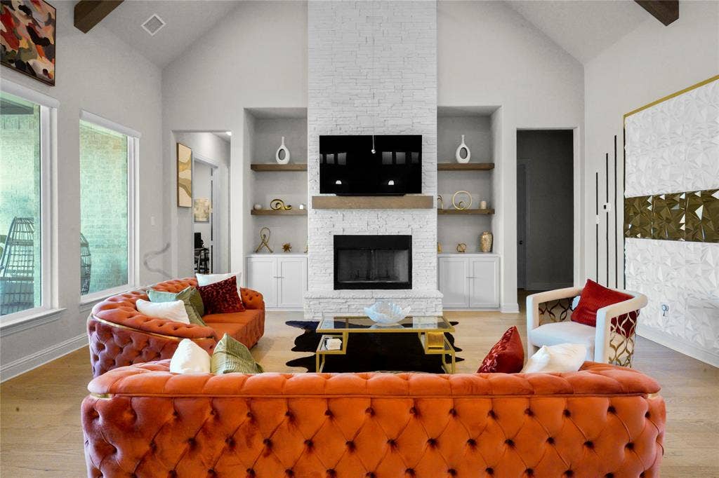 Vaulted ceiling living area featuring a stacked stone fireplace with a wood mantel