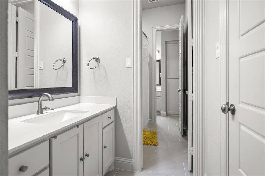 White vanity with shaker-style cabinetry, a solid surface countertop, and an undermount sink