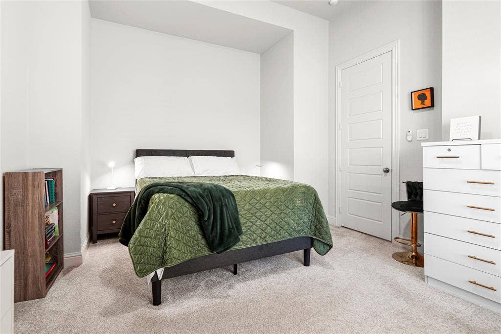 Carpeted room featuring light-colored walls and a five-panel interior door