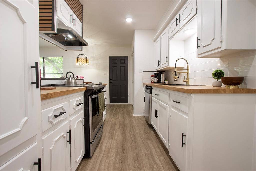 1205 Augusta Road, Benbrook, TX 76126 Galley kitchen featuring white cabinetry with matte black hardware, wood-finish countertops, subway tile backsplash, and wood-finish flooring