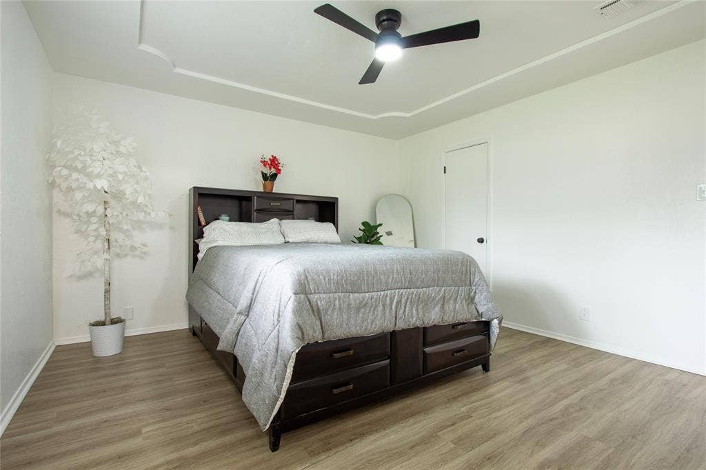 1205 Augusta Road, Benbrook, TX 76126 Spacious room featuring light wood-finish flooring, a tray ceiling, and a modern ceiling fan with integrated lighting