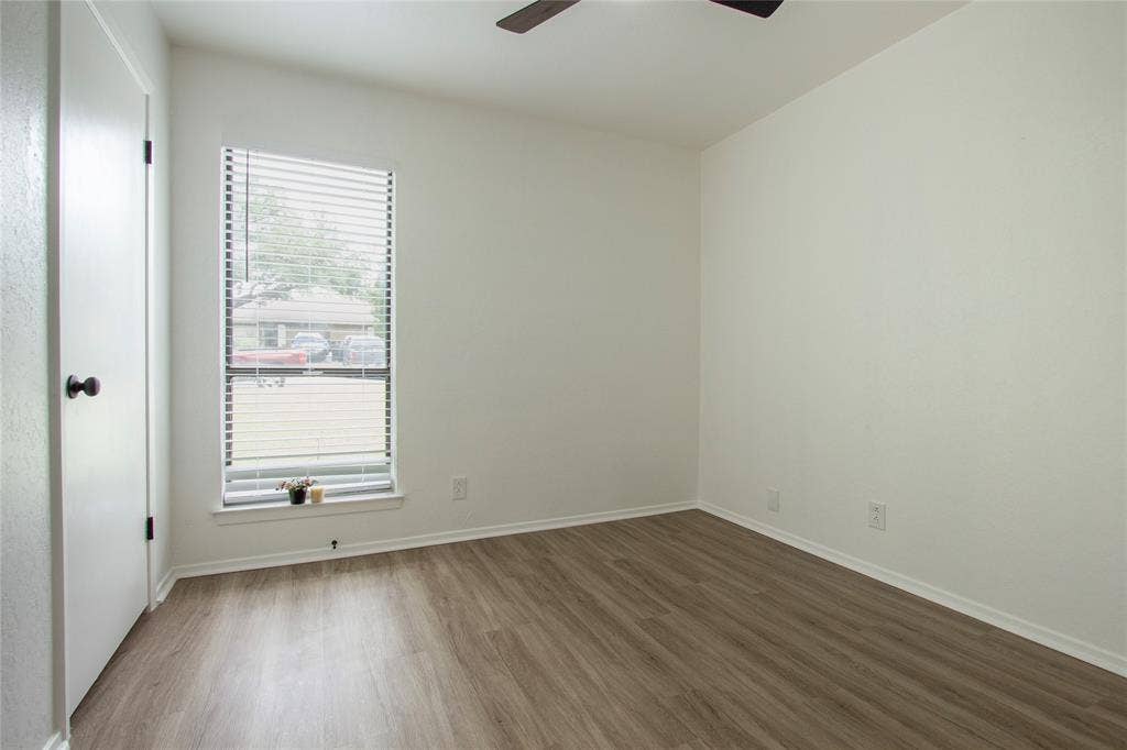 1205 Augusta Road, Benbrook, TX 76126 Room with wood-finish flooring, a single window with blinds, and a dark-toned ceiling fan